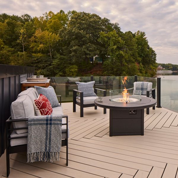 A side view of the Trex dock rooftop deck with a fire table lit and Trex X-Series Frameless glass highlighting the view.